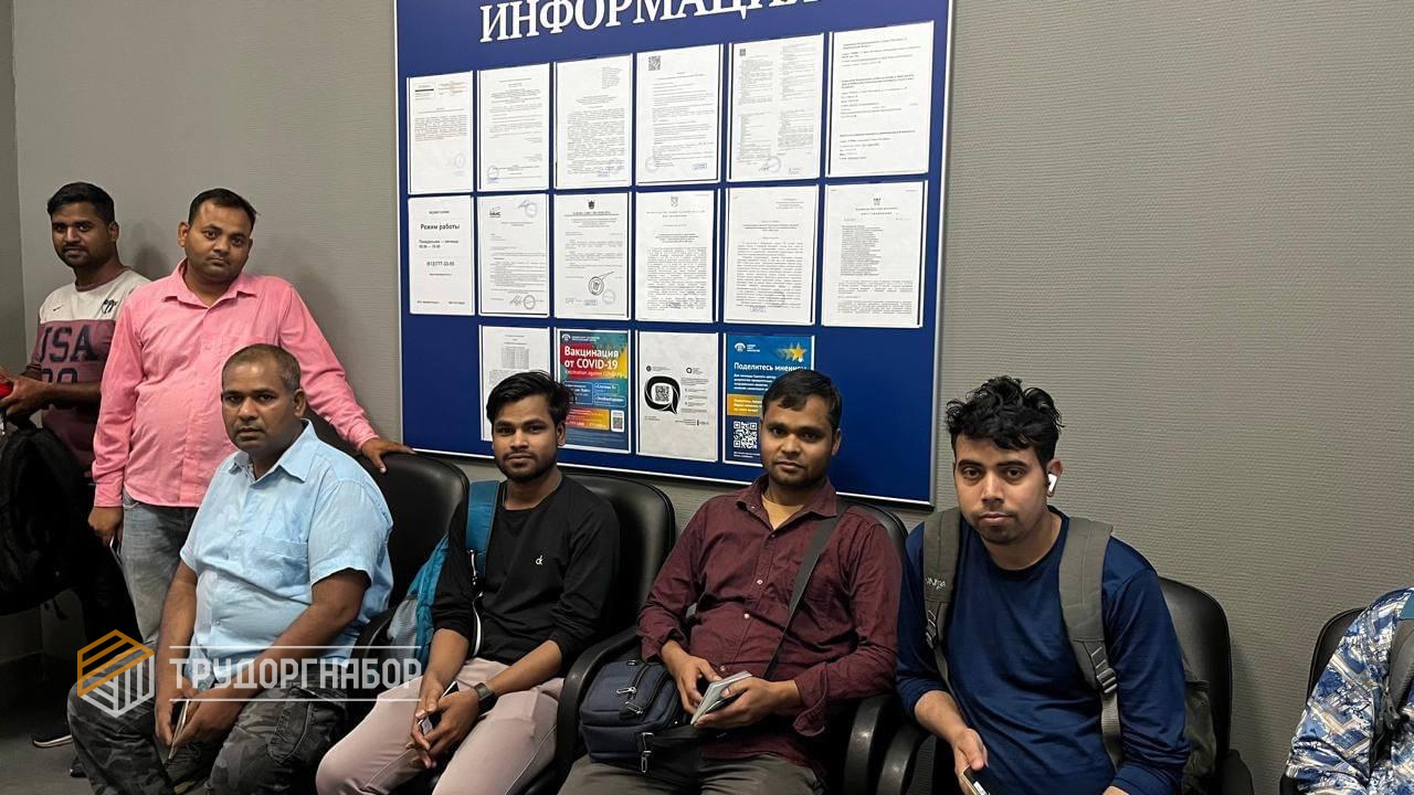 Люди сидят на стульях возле информационного стенда